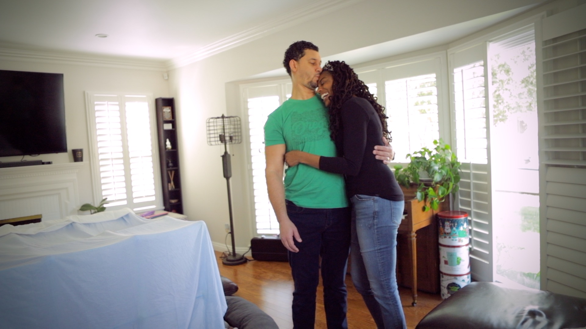 a man kisses his wife while she laughs